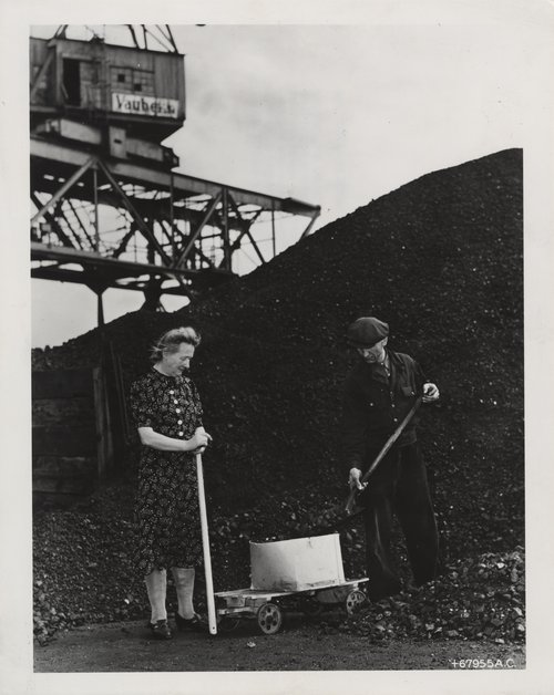 A man and a woman next to a large pile of coal. Coal 1