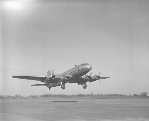 Black and white image of a four-engined transport aircraft about to land.