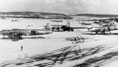 The snow-covered US airfield in Wiesbaden with three C-54 airplanes in the foreground.