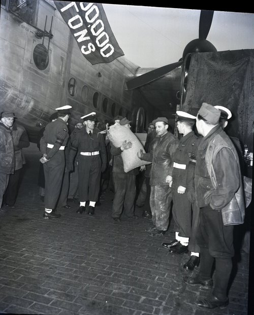 A British York aircraft adorned with a blue flag proclaiming '1,000,000 tons' is being unloaded by German workers on the Gatow airfield in Berlin. 