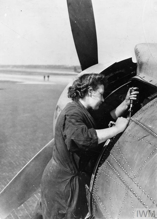 A woman working on an aeroplane's engine.