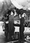 A man and a woman working on an aeroplane's engine.