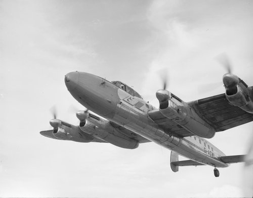 Eine Schwarzweißaufnahme zeigt ein viermotoriges Flugzeug im Flug.