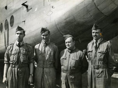 Vier Männer in Fliegerkleidung stehen vor einem Flugzeug.
