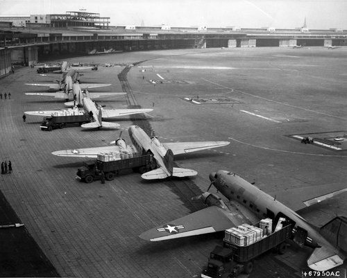 C-47 aeroplanes parked in line on an airfield.