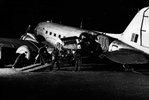 Black and white image of men moving an engine through the door of a transport aircraft.