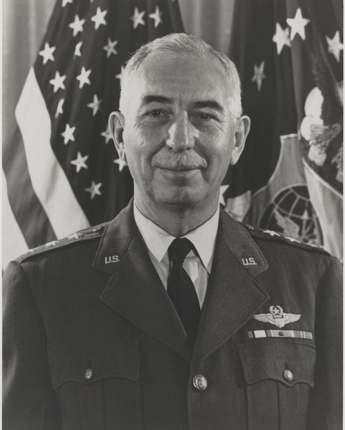 Portrait photo of General Joseph Smith in US Air Force uniform.  Flags of the United States and of the United States Air Force in the background.