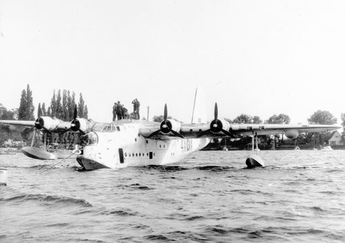A large four-engined flying boat, moored on water.