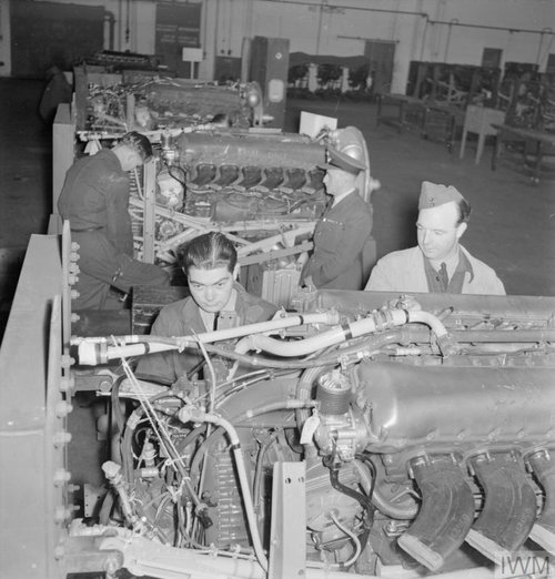 Black and white image of men working on a row of engines.